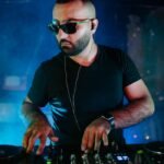 DJ focused on mixing beats at a nightclub with smoke and vibrant lighting.